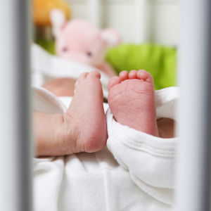 Spädbarnsfötter i en spjälsäng