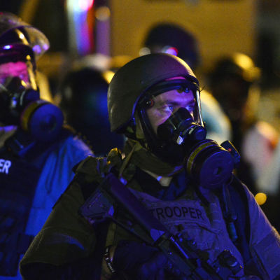 Police officers wearing gas masks stand guard during as demonstrators protest the shooting death of Michael Brown in Ferguson, Missouri, USA, 18 August 2014.
