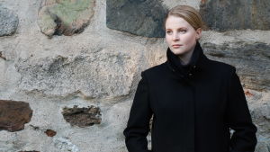 Mia Anderssén-Löf i Jakobstad är nytt prästombud i kyrkomötet. Mia Anderssén-Löf står framför en murad stenvägg.