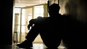 ungdom sitter ensam i en korridor