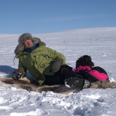 Mikko Peltsi Peltola makoilee jäällä kaverinaan musta koira.