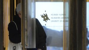 Studerande som går ut genom dörren vid Helsingfors universitet.