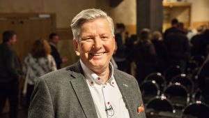 Mats Danielsson föreläser om vett och etikett. Mats danielsson har en grå kavaj och en så kallad myggmikrofon vid munnen.
