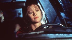 Annie (Meg Ryan) kan inte sluta tänka på den man hon hörde i radion. Närbild då Annie (Meg Ryan) sitter i en bil och funderar och ler.