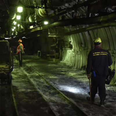Två arbetare står inne i en mörk kolgruva.