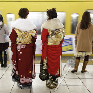 Kaksi kimonopukuista naista odottavat metrojunaa asemalaiturilla.