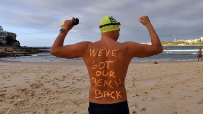 "Vi har fått tillbaka vår strand" står det på den här mannens rygg då han dyker i vid Bondi Beach i Sydney. Stranden öppnade efter att ha hållits stängd i fem veckor.