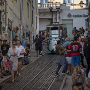 Lissabon lockar såväl turister som potentiell arbetskraft. En spårvagn på en brant sluttandet gata. Spårvagnen och väggarna har mycket graffiti på sig och på gatan finns det mycket människor.