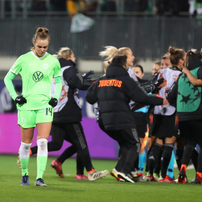 Wolfsburg-spelare ser ledsen ut med Juventus som firar i bakgrunden.