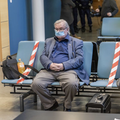 Pekka Kataja istuu oikeussalin aulassa asianajajansa kanssa.