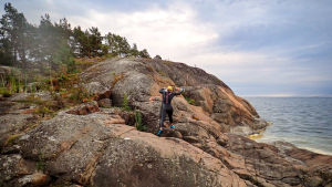 Tävlingsformen swim run går över klippor, vatten, skog och äng. En person i våtdräkt springer upp för klippstrand.