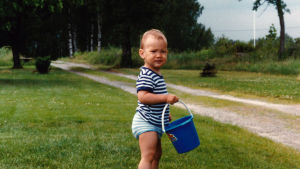 Som 15-åring flyttade Tim Sparv till England för att bli fotbollsproffs. Men det var i Oravais allt började. Tim Sparv som barn med blått ämbar i handen på gräsmatte vid sandstig.