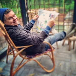 Owe Salmela istuu korituolissa ja lukee lehteä.