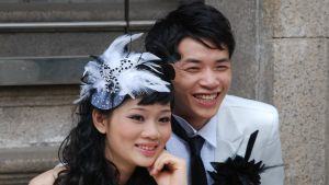 I Hongkong ordnades det knappt 30 000 bröllop i fjol. Siffran minskar varje år även om invånarantalet fortsätter att öka. Ett brudpar från Hongkong blir fotograferade. Bruden har en stor, vit fjäderprydnad i sitt hår.