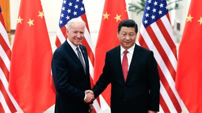 Joe Biden och Xi Jinping skakar hand. I bakgrunden USA:s och Kinas flagga.