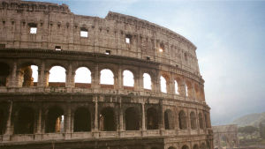 Rooman Colosseumin ylimmät kerrokset sinistä taivasta vasten.