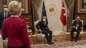 Ingen sittplats erbjöds Ursula von der Leyen under mötet med Turkiets president den 6 april. En kvinna i röd tröja står med ryggen mot kameran till vänster, och tittar på två sittande, kostymprydda män i fina fåtöljer.