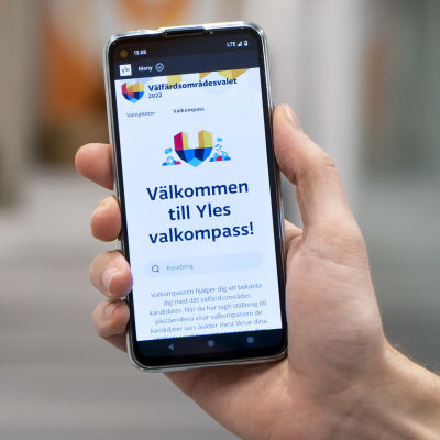 Närbild på mobiltelefon som visar upp startsidan för Svenska Yles valkompass med texten "Välkommen till Yles valkompass"