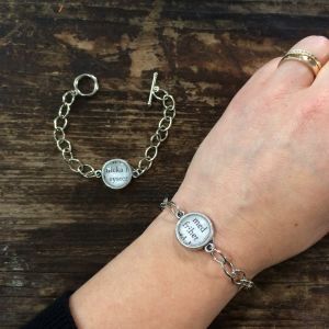 Armband med dekoration av en några ord från en boksida under en glasbubbla.