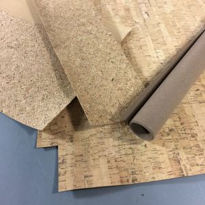 Erilaisia kuvioituja korkkikankaita ja paperinahkoja rullalla. Korkkikangas ja nahkapaperi