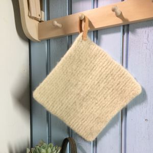 Stickad och tovad grytlapp med läderögla. tovad grytlapp med läderögla hänger på en krok