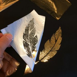 Tekstiilifolion kultaväri tarttuu niihin kohtiin, joissa on liimapastaa. Kullanväristä tekstiilifolio nostetaan kankaalta ja kuvio esiintyy.