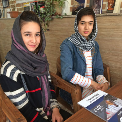 Kvinnorna Shaqaiq och Arzoo ler mot kameran på ett kafé i Kabul.