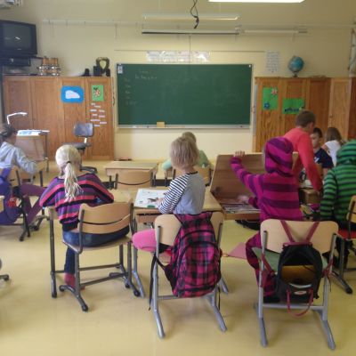 Elever sitter i ett klassrum med stolar och pulpeter