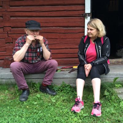 Nainen ja mies istuvat kotiseutumuseon rakennuksen edessä.