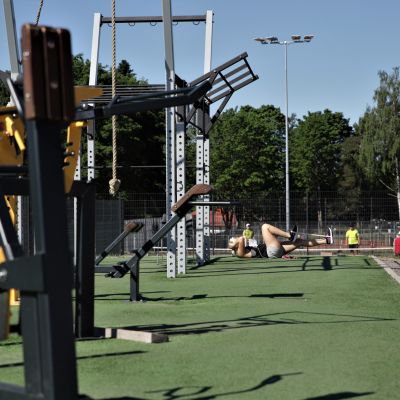 Nuori nainen tekee vatsalihasliikkeitä Kimpisen urheilukentän vieressa.
