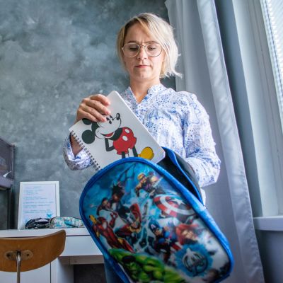 Tiina Weisell laittaa poikansa koulutarvikkeita reppuun.