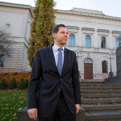 Johtokunnan neuvonantaja Mika Pösö seisoo Suomen Pankin pääkonttorin ulkoportaiden edessä. Taustalla näkyvä J. V. Snelmanin patsas on saanut kaulaansa siniseen nauhaan sidotun Abloy-avaimen.