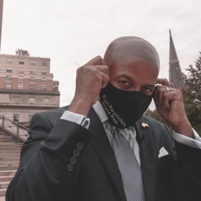 Demokraattiedustaja Ron Reynolds asettelee kasvoilleen maskia.
