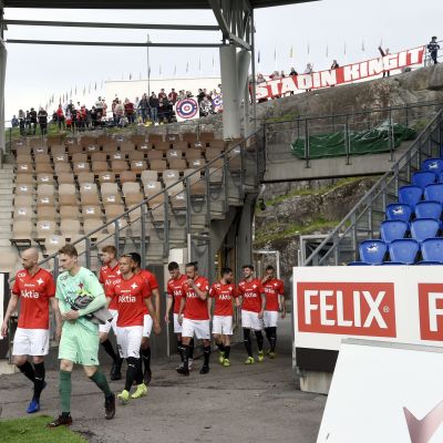 HIFK-spelarna går in på plan med supportarna i bakgrunden.