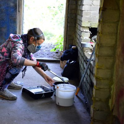 Katutaiteilija Okeiko omenapuutarhateosken kimpussa.