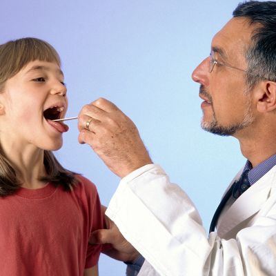 Barnläkare undersöker en flickas hals