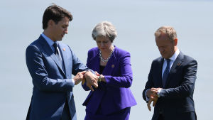 Justin Trudeau, Theresa May och Donald Tusk håller koll på tiden. Justin Trudeau, Theresa May och Donald Tusk tittar på sina klockor under G7-mötet i Kanada.