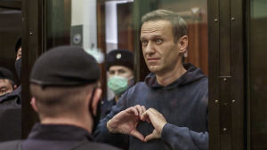Den fängslade oppositionspolitikern Aleksej Navalnyj. Navalnyi muodostaa käsillään sydämen oikeussalin lasikopissa, ympärillä poliiseja