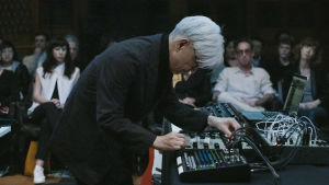 Ryuichi Sakamoto konsertissa elektronisen laitteen äärellä. Kuva async-konsertista..