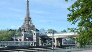 Stubb studerade bland annat i Paris och Brugge. Järnvägsspår med bro och ett fotomontage av Eiffeltornet i bakgrunden.
