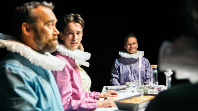 Skådespelare i färggranna kläder kring ett matbord i Unga Teaterns pjäs Fem mål mat.