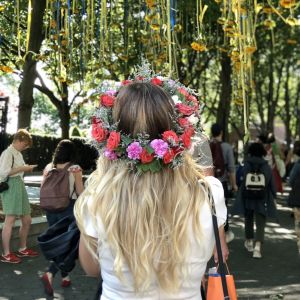 Kvinna med blomsterkrans på huvudet beundrar solrosarrangemang vid ingången till Battery Park