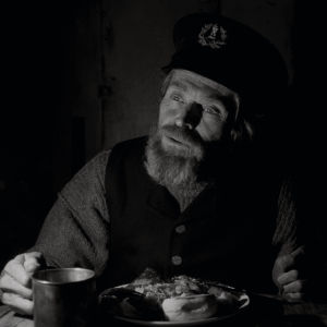 Hur länge har vi varit här? Fem veckor? Två dagar? Thomas (Willem Dafoe) behöver hjälp att minnas. Thomas (Willem Dafoe) sitter vid bordet och äter.