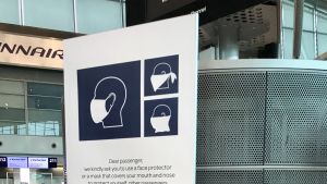 Både resenärer och personal ombeds använda munskydd när de vistas på Helsingfors-Vanda flygplats. Skyltar påminner om säkerhetsavstånd och hygien och det hörs karantänsanvisningar i högtalarna med jämna mellanrum. Instruktioner om användning av munskydd.