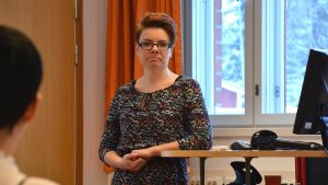Sofia Mitts-Björkblom. Sofia Mitts-Björkblom står och lutar sig mot ett databord.