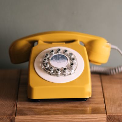 En gul trådtelefon på ett bord.
