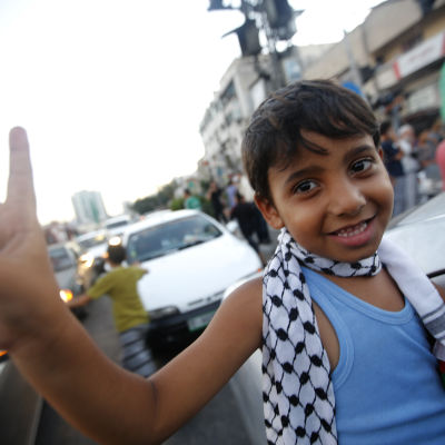 Palestinsk pojke visar segertecken under firandet av eldupphöret i Gaza.