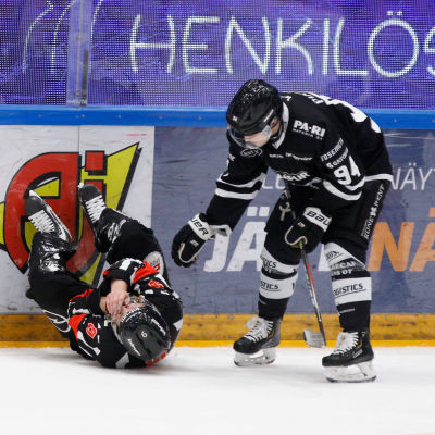 Domaren Jarno Heikkinen ligger på isen, Henrik Larsson lutar sig ner