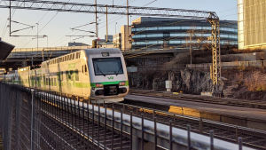 Lokaltåget till Lojo avgår snart från spår 1. Ett lokaltåg kör i soluppgången förbi Kottby station i Helsingfors.