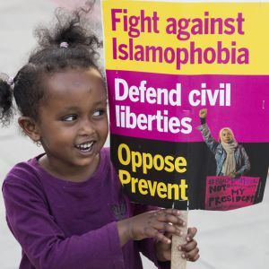 Flicka håller upp en skylt med texten: Kämpa mot islamofobi. Flicka håller upp en skylt med texten: Kämpa mot islamofobi